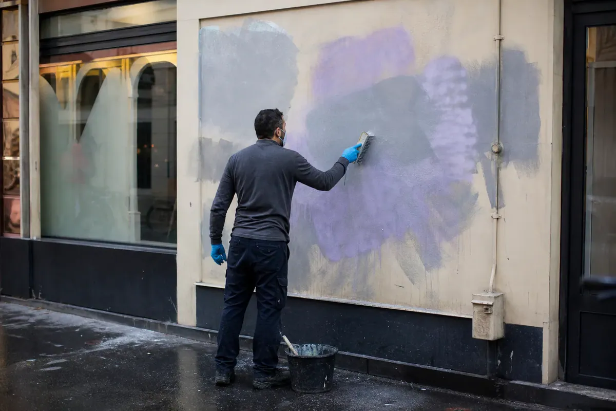 Illustration : technicien frottant à la brosse la façade d'un commerce lors d'un nettoyage de graffitis
