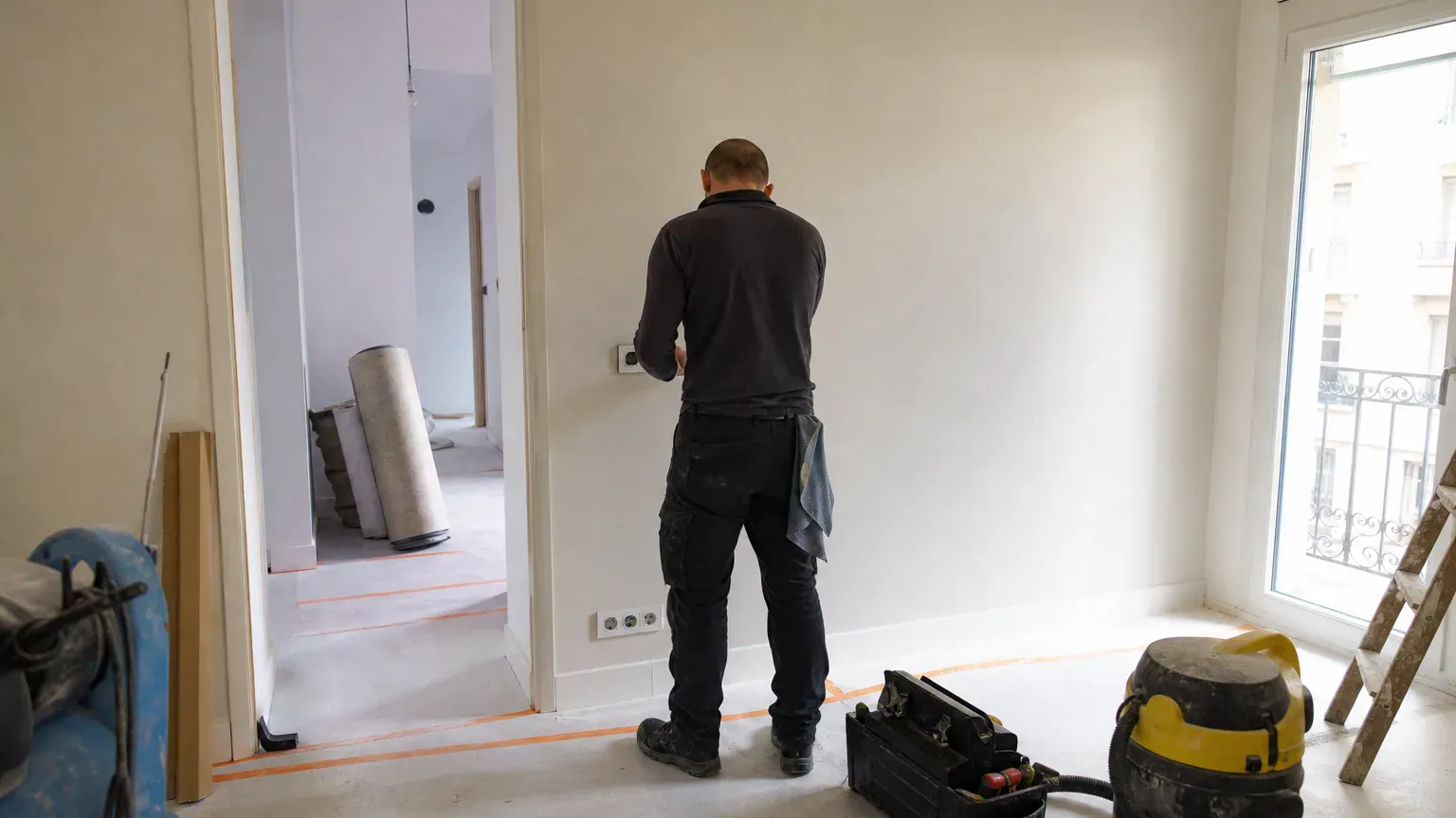 Agent vérifiant des interrupteurs neufs poussiéreux pendant la checklist de nettoyage de fin de chantier