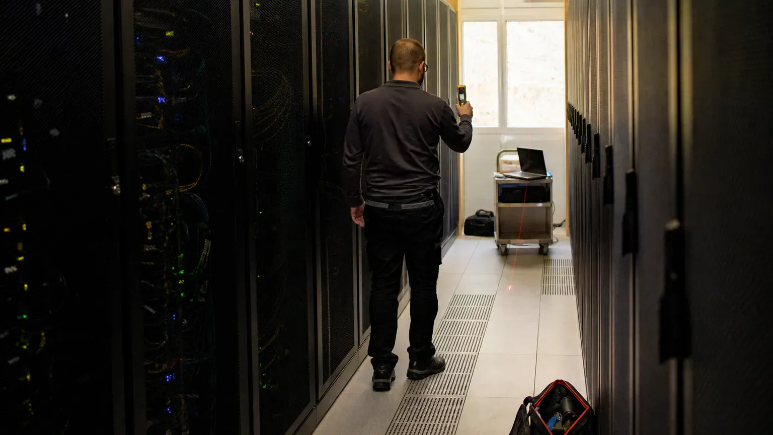 Technicien mesurant une allée de baies informatiques pour chiffrer le coût du nettoyage d'un data center