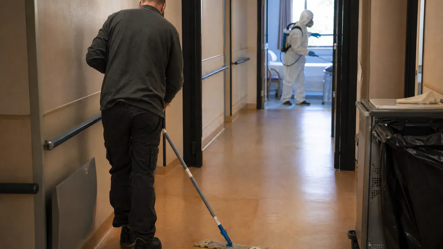 Agent de nettoyage et technicien de décontamination en combinaison travaillant dans le même logement