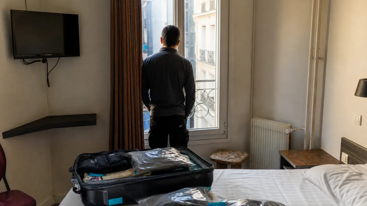 Personne dans une chambre d'hôtel avec ses valises, relogée temporairement après un incendie