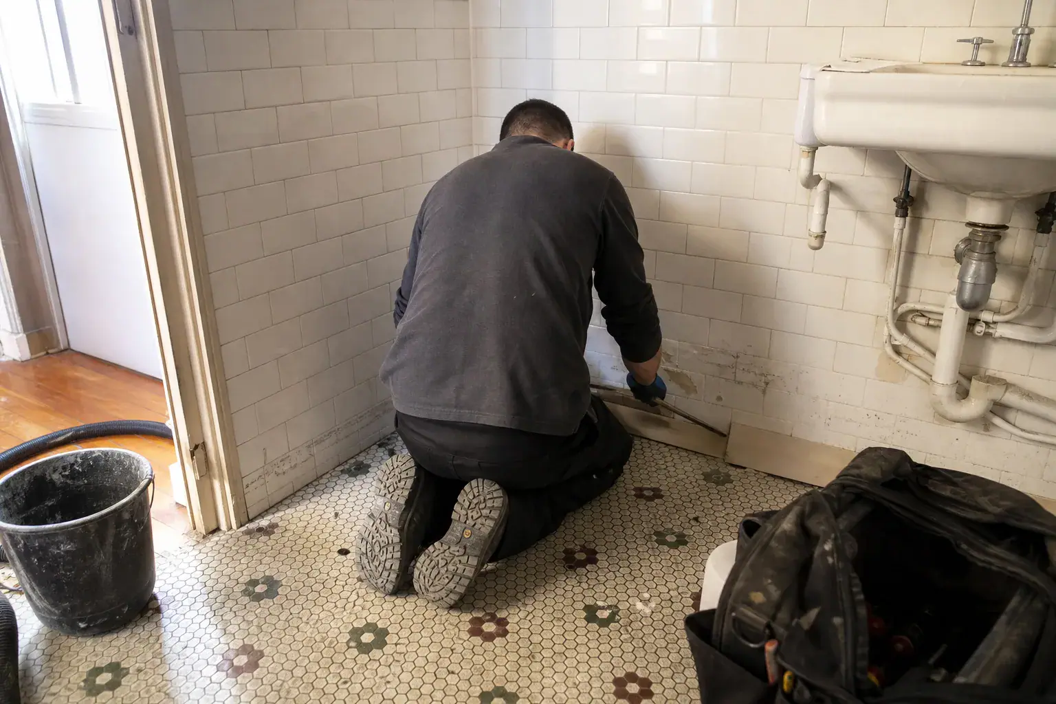 Dépose d'une plinthe gonflée par l'eau dans une salle de bains des Hauts-de-Seine après dégât des eaux
