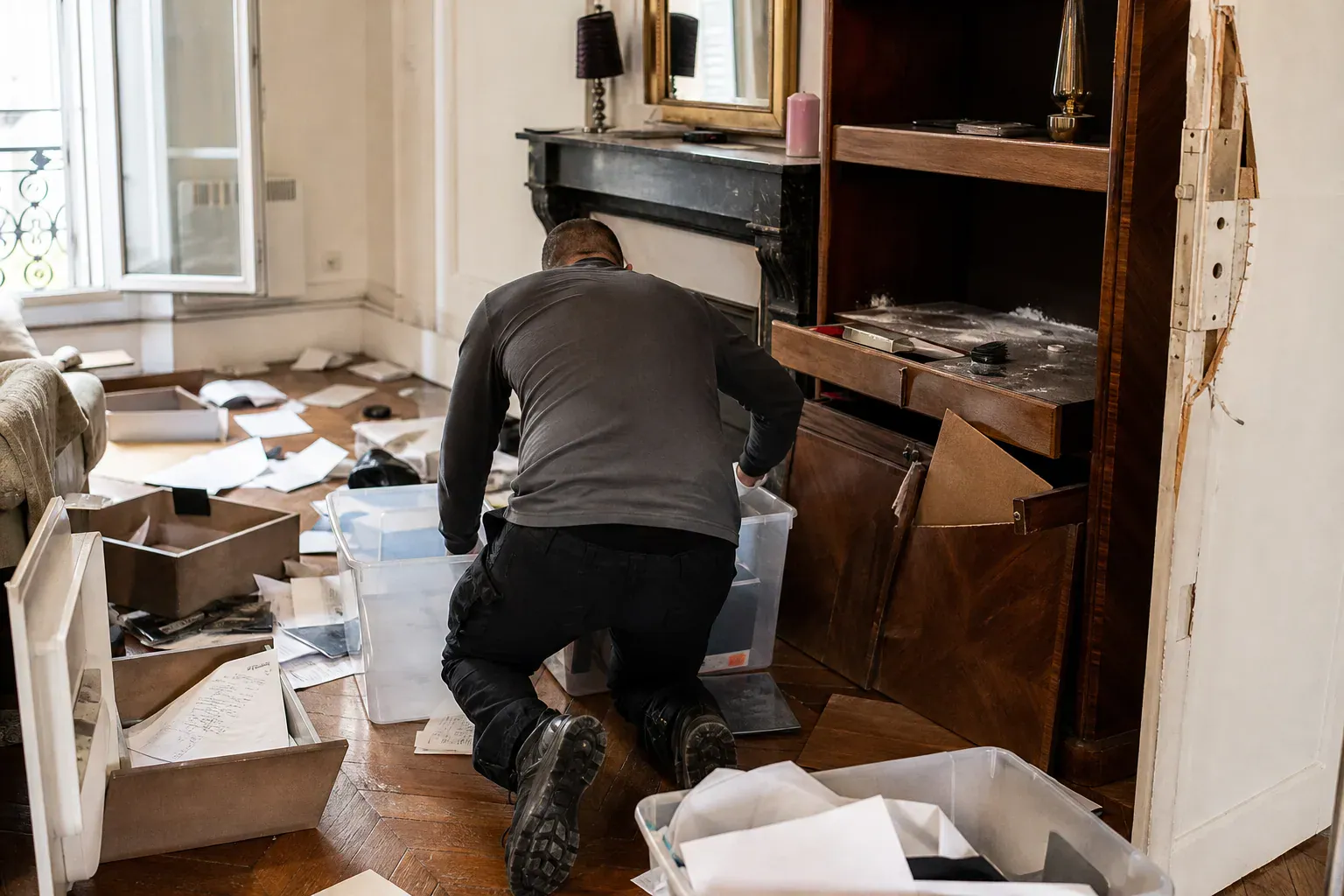 Technicien rangeant un salon parisien mis à sac lors d'un nettoyage après cambriolage