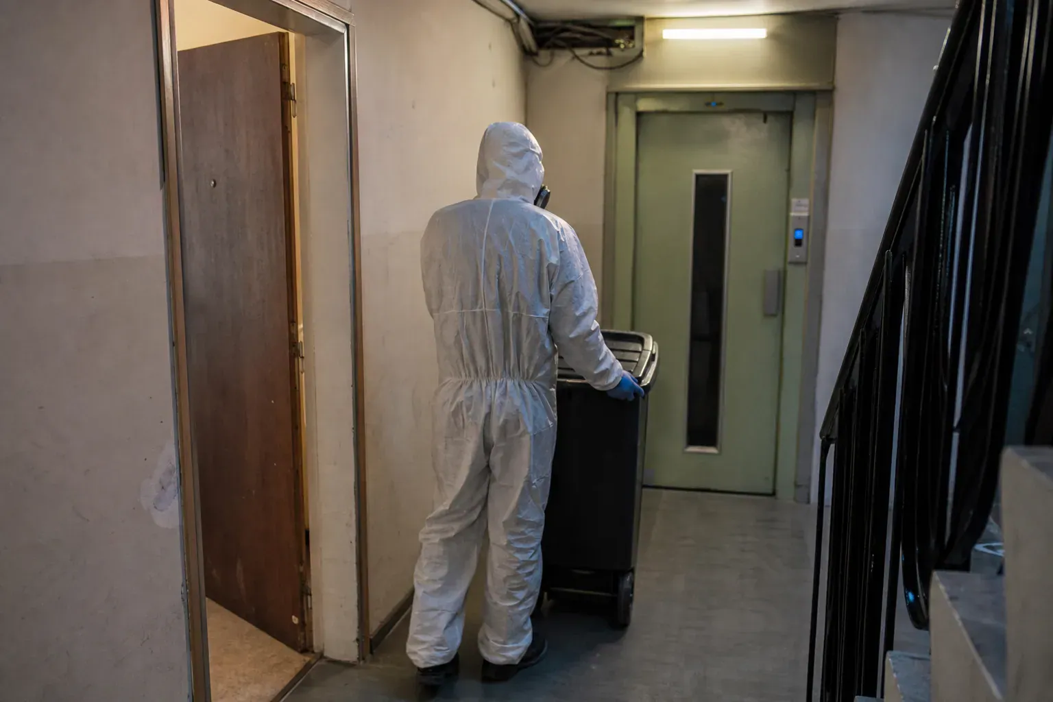 Technicien sortant un bac de déchets d'un appartement en Seine-Saint-Denis après un nettoyage après décès