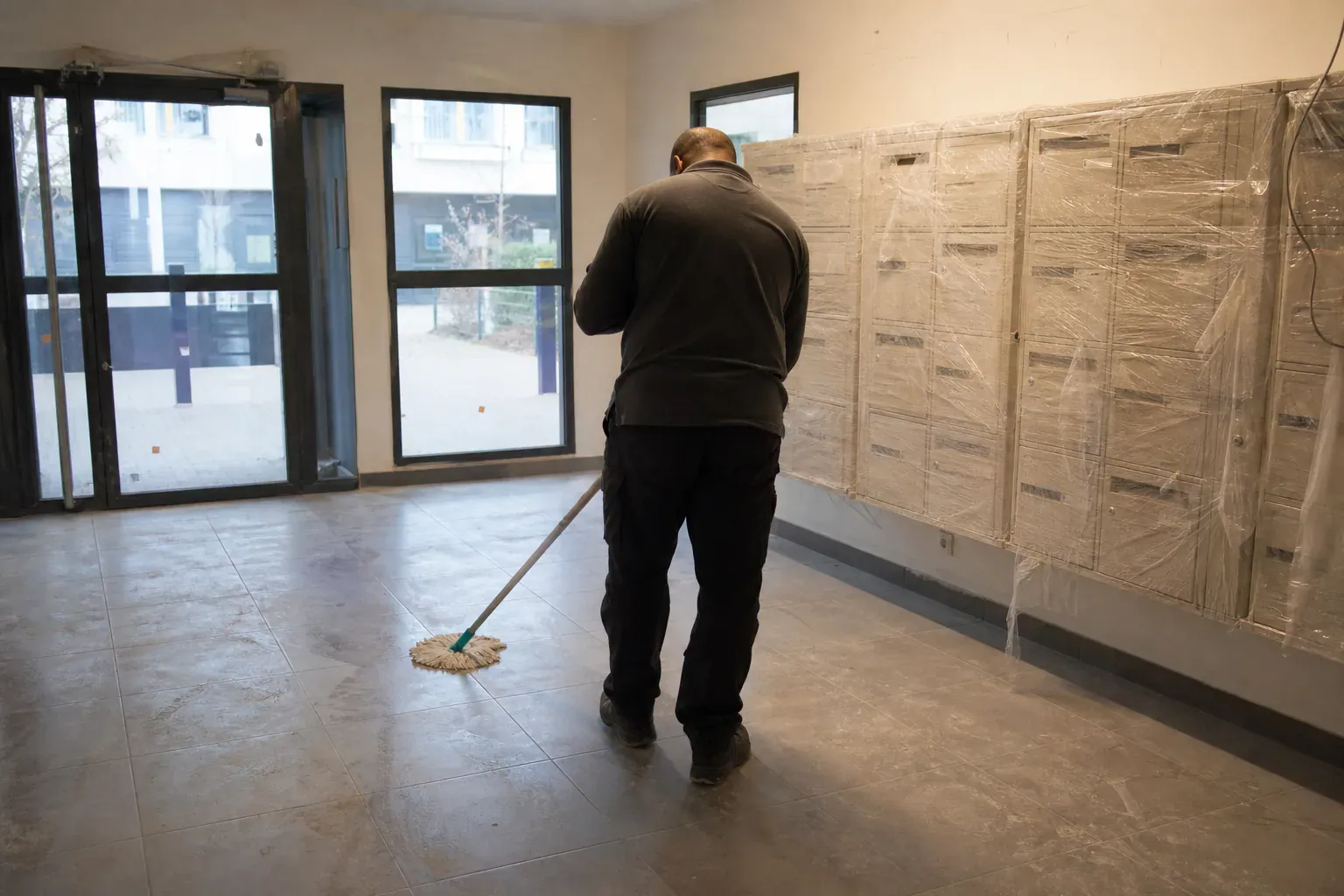 Lavage du sol poussiéreux dans le hall d'une résidence neuve du Val-d'Oise après travaux