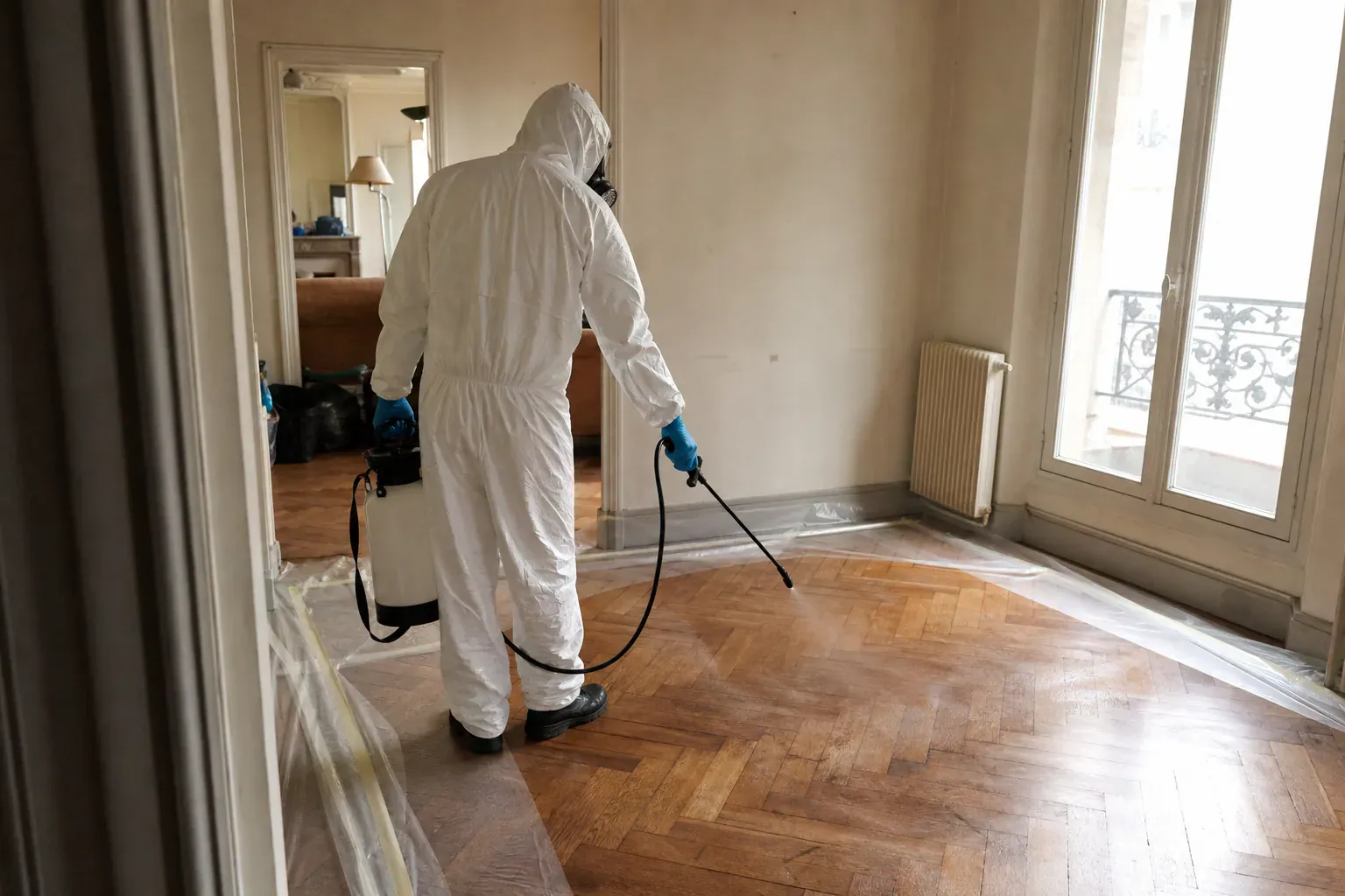 Technicien en combinaison désinfectant un parquet à Paris lors d'un nettoyage de scène de crime