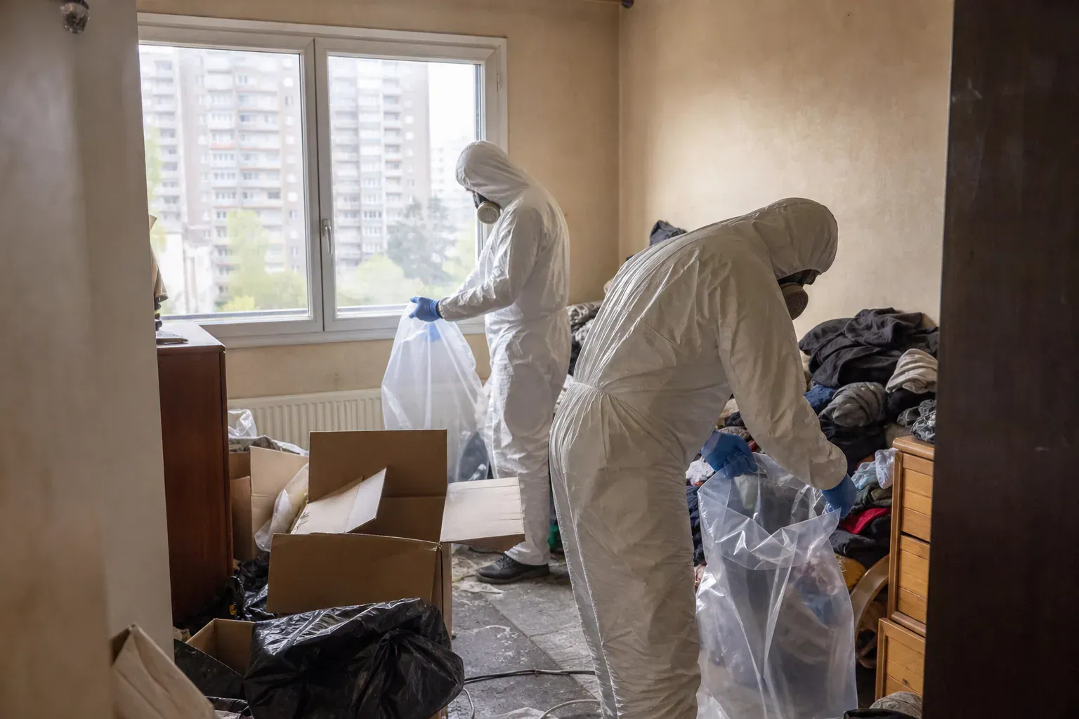 Remplissage de sacs dans une chambre encombrée d'un appartement du Val-d'Oise, syndrome de Diogène